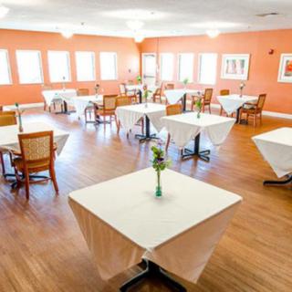 An empty dining room with neatly arranged tables and chairs, featuring a warm color scheme.