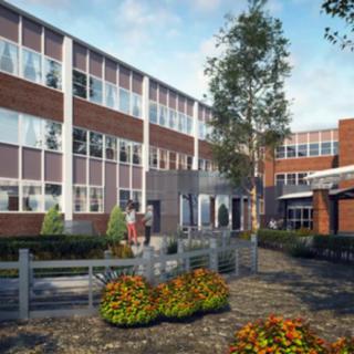 A modern school building surrounded by a landscaped garden during the daytime.