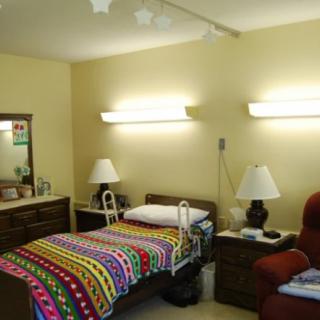 A cozy room with a hospital bed featuring a vibrant, colorful blanket and warm lighting.