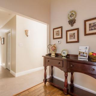 A warmly lit hallway featuring a wooden console table adorned with decorative items and framed artwork on the wall.