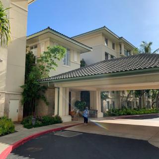 A tropical-style hotel entrance with a driveway and lush landscaping.