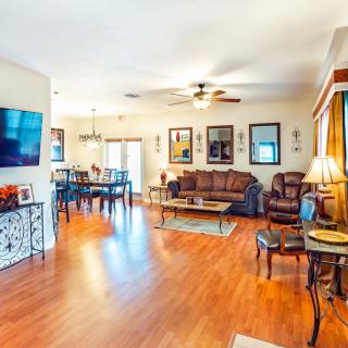 A spacious living room with a connected dining area features hardwood flooring, warm lighting, and stylish decor.