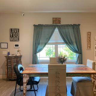 A cozy dining room with a table and chairs, complemented by wall decor and natural light through the window.