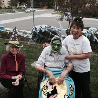 A group of people in Halloween costumes, photographed outdoors with festive decorations.