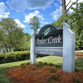 Entrance sign for Poplar Creek surrounded by trees and greenery.