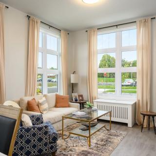 A cozy, well-lit living room with a comfortable sofa and large windows.
