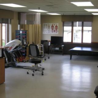 A physical therapy room with exercise equipment and therapy tables.