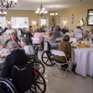 Seniors enjoying a communal meal in a dining hall, engaging in conversation and socializing.