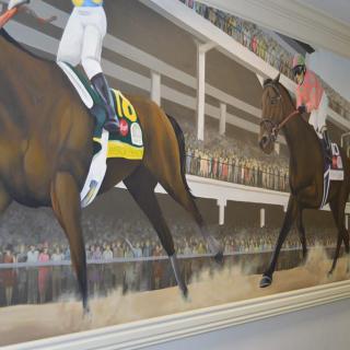 A mural depicting a horse race with jockeys and a crowd of spectators.