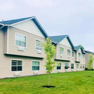 An exterior view of a residential apartment building with well-maintained lawns and young trees.