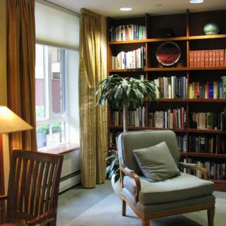 A cozy reading nook with an armchair and a bookshelf filled with books.
