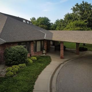 A one-story building with a covered driveway and well-maintained landscaping under a clear sky.