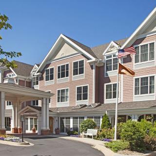 A multi-story residential building with an entrance and flags waving outside.