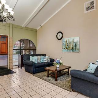 A cozy living room with sofas and a coffee table, decorated with artwork and a wall clock.