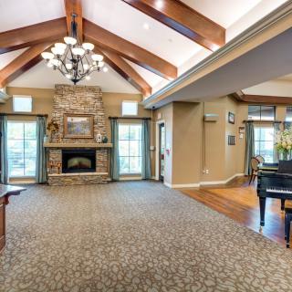 A spacious living room with a vaulted ceiling, featuring a fireplace and a grand piano.
