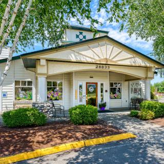 A charming building entrance surrounded by trees and bushes.