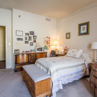 A cozy and well-decorated bedroom featuring a single bed, wooden furniture, and various wall decorations.