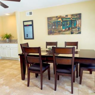 A dining room with a wooden table and chairs, featuring wall art and neutral tones.