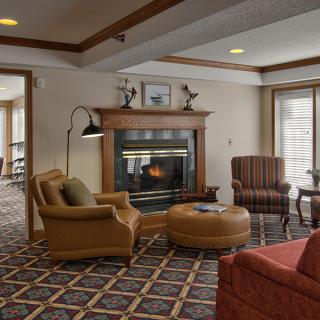 A cozy living room featuring a fireplace, comfortable armchairs, and a patterned carpet.