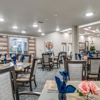 A spacious and well-lit indoor dining area with neatly arranged tables and chairs, featuring elegant table settings.