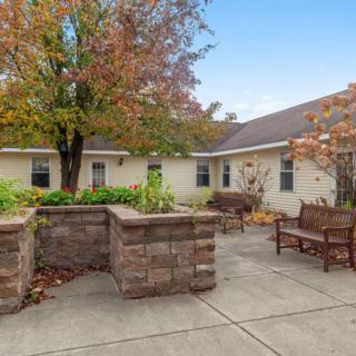 A peaceful courtyard with benches and a tree, showcasing autumn colors.