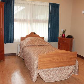 A simple and cozy bedroom featuring a single wooden bed and blue curtains.