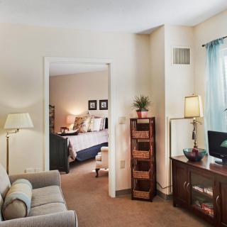 A cozy living room with a view into a neatly arranged bedroom, featuring comfortable furniture and stylish decor.