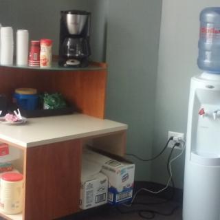 An office breakroom corner featuring a coffee station and a water cooler.