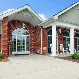 A brick building entrance with large glass doors and white columns.