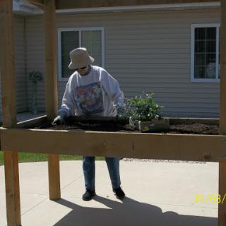 A person engaging in gardening activities at a raised bed, enjoying the outdoors.