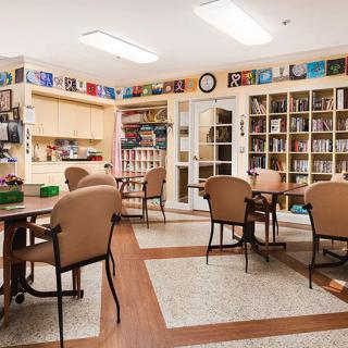 A cozy library with bookshelves, tables, and chairs arranged for reading.