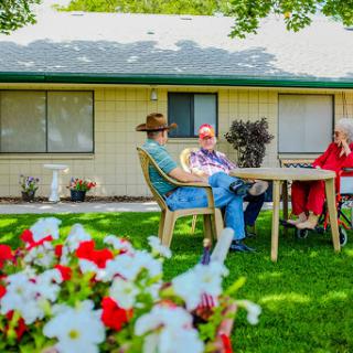 A pleasant afternoon in the garden, where friends enjoy each other's company surrounded by blooming flowers.