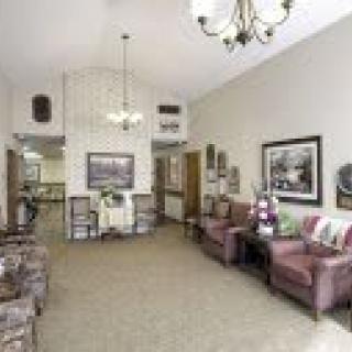 A cozy living room with plush chairs, a chandelier, and wall art.
