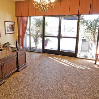A well-lit office with a wooden desk, large windows, and elegant decor.