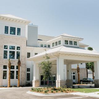 A modern building with a covered entrance and surrounding palm trees.