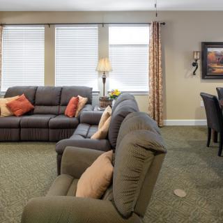 A cozy living room with comfortable sofas and a dining area in the background.