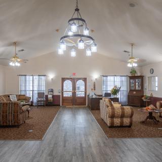 A spacious living room with elegant chandeliers, comfortable sofas, and wooden flooring.