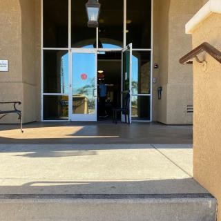 Entrance to a building featuring glass doors and steps under a clear sky.