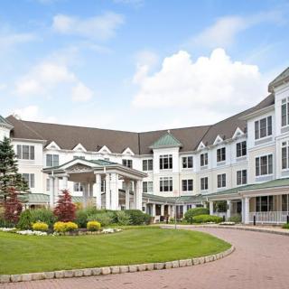 A large, elegant residential building with well-maintained landscaping and a clear blue sky.