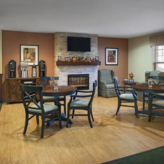 A cozy living room with a fireplace, tables, and chairs arranged for seating.