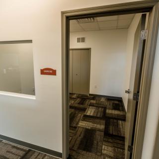 An interior view of an office hallway with an open door leading into an empty room.