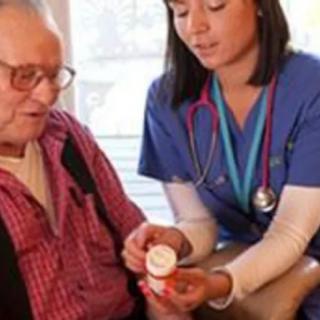 A nurse assists an elderly man with his medication during a home visit.