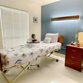 A serene hospital room featuring a patient bed, bedside table, and natural light from the window.
