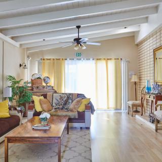 A cozy and bright living room with natural light, featuring comfortable furniture and decorative elements.