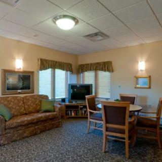 A cozy living room with a couch, table, chairs, and a television.