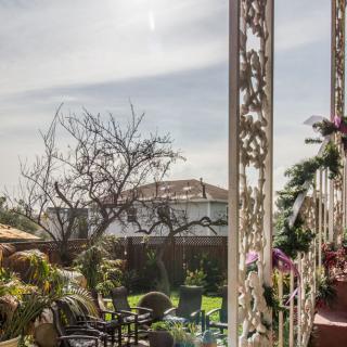 A sunny garden with chairs and lush greenery viewed from a decorated patio.