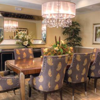 A beautifully designed dining room featuring a wooden table surrounded by patterned upholstered chairs, elegant lighting, and decorative plants.