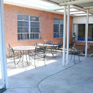 A covered patio area with metal outdoor furniture and a brick wall backdrop.