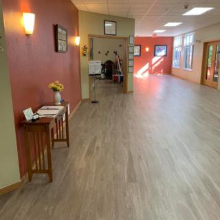 A spacious hallway with wooden flooring and vibrant red walls, leading to a reception area.