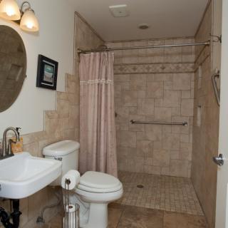A tiled bathroom with a walk-in shower, sink, toilet, and mirror.